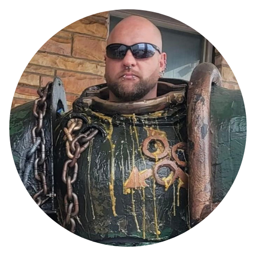 Staff Member Nathan H.
Bald man wearing sunglasses with surly expression in an impressive space marine armor cosplay